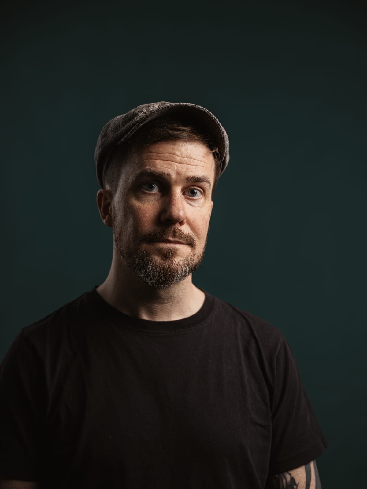 Christoph Landes wearing a flat cap against a dark teal background