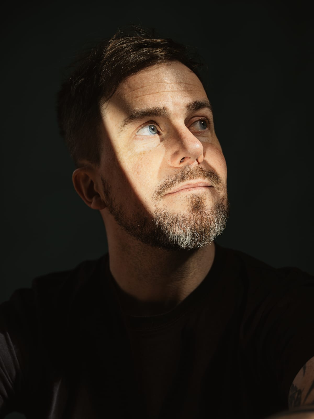 Portrait of Christoph Landes looking upward against a dark teal background