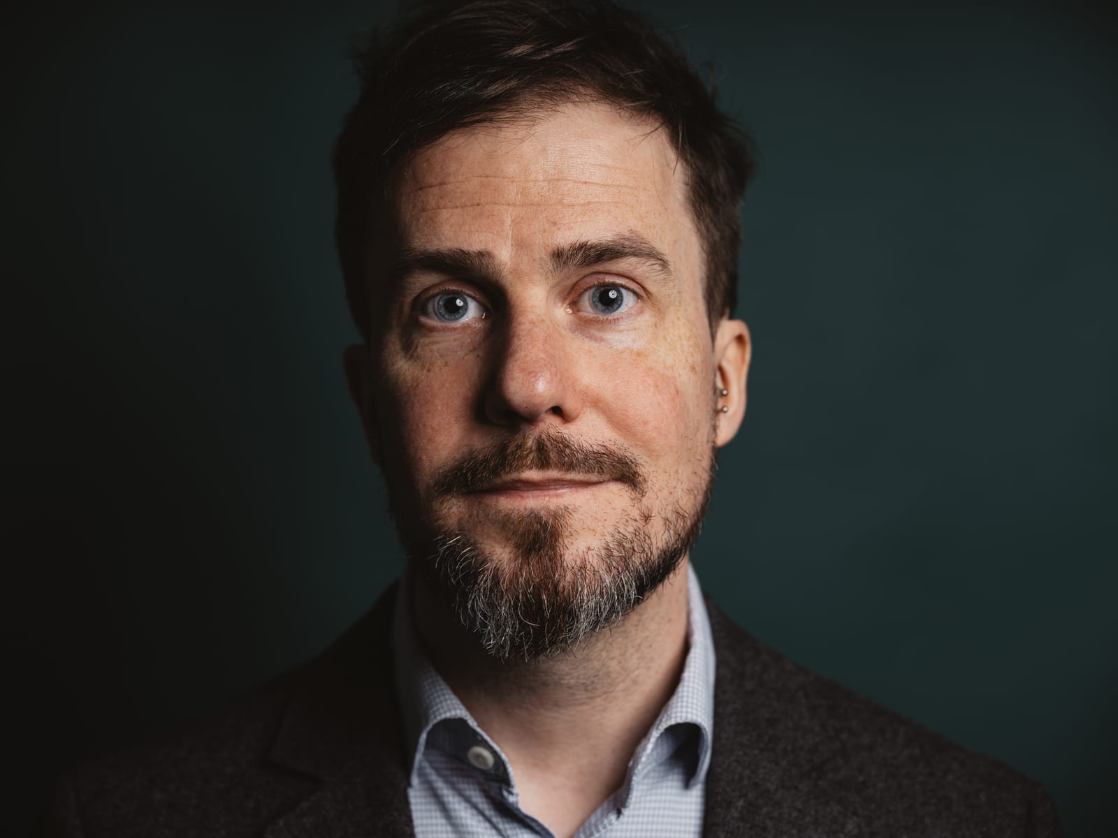 Christoph Landes in a blazer against a dark teal background
